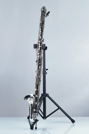 Eine silberfarbene Hammerschmidt B-Bassklarinette Orchester OH 820 steht auf einem schwarzen Stativ vor einem hellgrauen Hintergrund.