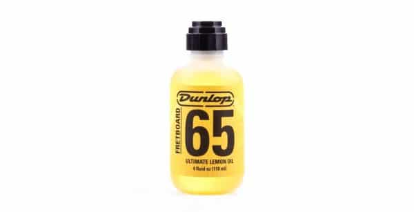 Eine durchsichtige Plastikflasche gefüllt mit gelbem Dunlop Formula No. 65 Ultimate Lemon Oil, verschlossen mit einem schwarzen Drehverschluss, steht auf einem weißen Hintergrund.
