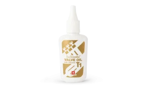 Eine weiße Flasche La Tromba T1 Ventil-Öl mit Silikon steht aufrecht, das Etikett zeigt ein goldenes X mit grafischen Elementen und den Schriftzug "Valve Oil with silicone T1" sowie ein Schweizer Kreuz.