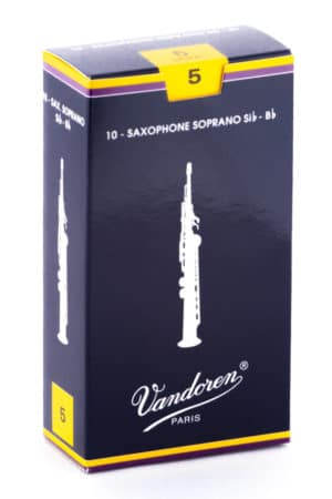 Eine dunkelblaue und gelbe Pappschachtel mit der Aufschrift Vandoren Paris ist abgebildet, auf der Vorderseite zwei weiße Saxofon-Illustrationen und oben eine gelbe „5“ zu sehen sind.