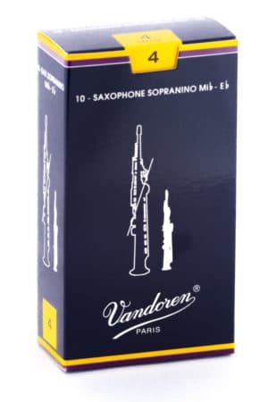 Eine dunkelblaue Kartonschachtel mit gelben Akzenten und einer weißen Abbildung von zwei Saxophonblättern trägt den Aufdruck "Vandoren Paris" und die Bezeichnung "10 - SAXOPHONE SOPRANINO Mib - Eb".