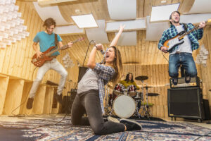 Eine Band, bestehend aus einer Sängerin und drei Musikern mit Gitarren und Schlagzeug, probt in einem mit hellem Holz verkleideten Raum, dessen Wiedereröffnung am 13. Dezember 2021 stattfand.