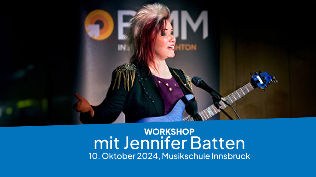 Jennifer Batten, eine Frau mit auffälliger, rot-blonder Frisur und schwarzer Jacke mit goldenen Fransen, steht vor einem Mikrofon und einer E-Gitarre, während im unteren Bildbereich in blauer Schrift ein kostenloser Workshop mit ihr am 10. Oktober 2024 in der Musikschule Innsbruck angekündigt wird.