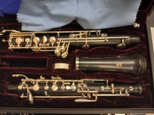 Eine gebrauchte, schwarze Yamaha Oboe YOB 241 liegt zerlegt in ihrem burgunderroten Koffer zusammen mit einem blauen Putztuch.