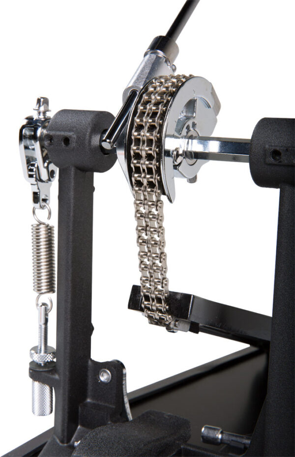 Nahaufnahme eines Roland RDH-100 Kick Drum Pedals, bei dem die silberne Kette deutlich im Fokus steht, die einen Teil des schwarzen Metallmechanismus verbindet und eine Feder sichtbar ist.