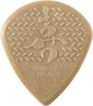 Nahaufnahme eines beigen Dunlop Matthew K. Heafy Custom Max-Grip Jazz III Plektrums mit Textur sowie einem Schriftzug und dem Schriftzug "Dunlop U.S.A.".