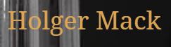 Das Bild zeigt den Namen "Holger Mack" in ockerfarbener Schrift vor einem Hintergrund, der links teilweise aus verschwommenen, vertikalen, hellgrauen Linien und rechts aus einem dunklen, unscharfen Bereich besteht.