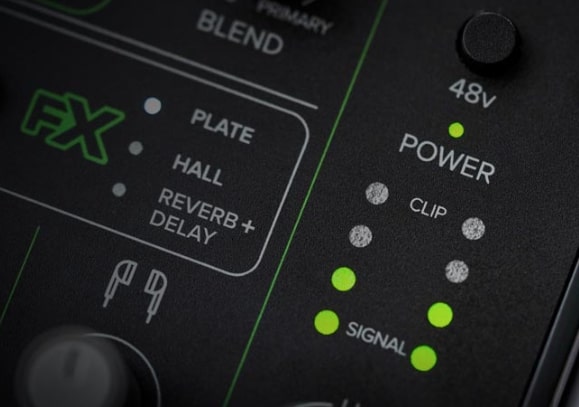 Detailansicht eines schwarzen Audio-Mixers mit grünen Akzenten, beleuchteten grünen LEDs für Stromversorgung und Eingangssignal sowie der Aufschrift "FX", "POWER", "SIGNAL" und verschiedenen Reverb-Optionen.