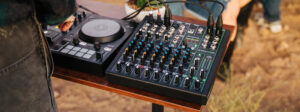 Ein schwarzer DJ-Controller und ein schwarzes Mischpult mit vielen Reglern stehen auf einem Holztisch.