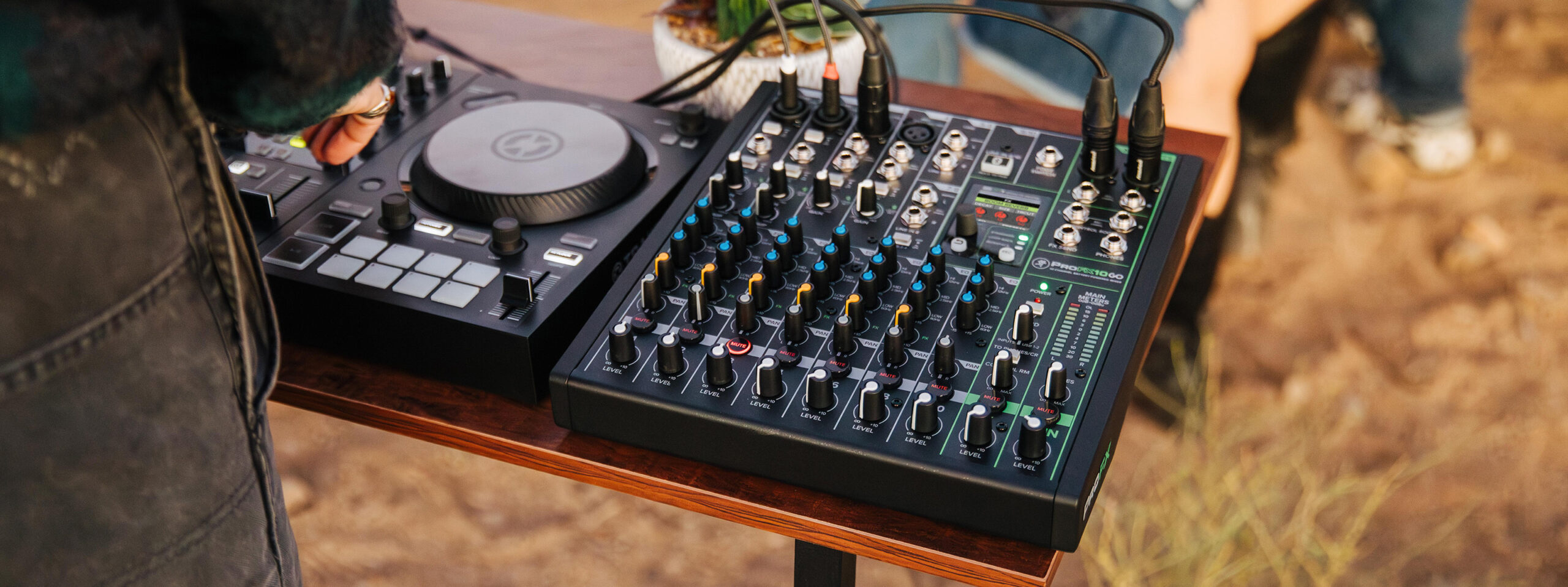 Ein schwarzer DJ-Controller und ein schwarzes Mischpult mit vielen Reglern stehen auf einem Holztisch.