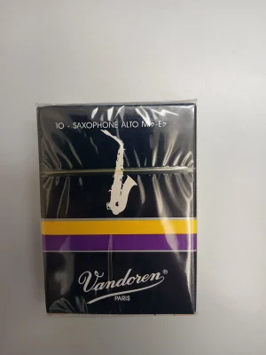 Auf hellgrauem Grund liegt eine rechteckige, dunkelblau-lila verpackte Schachtel Vandoren Altsaxophonblätter mit einem weißen Saxophon-Symbol und einem gelb-lila Streifen.