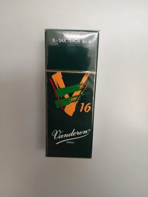 Eine dunkelgrüne Packung Vandoren Tenorsaxophon-Blätter V16, Stärke 1,5, mit orangefarbenem V16-Logo und grünen, horizontalen Streifen liegt auf einem hellen Untergrund.