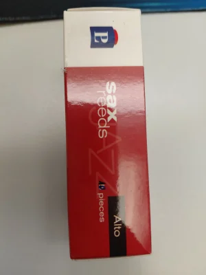 Auf einem hellen Untergrund liegt eine rote und weiße Schachtel mit der Aufschrift "sax reeds Jazz Alto" und dem Logo von Peter Leuthner; es handelt sich um Blätter für ein Altsaxophon in der Stärke 2,5.