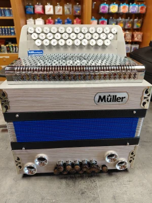 Das Bild zeigt eine gebrauchte, helle, dreireihige steirische Harmonika der Marke Müller mit blauem Balg, silberfarbenen Knöpfen und Verzierungen.