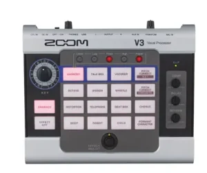 Ein Zoom V3 Vocal Prozessor ist auf einer weißen Oberfläche abgebildet, der eine graue Gehäusefarbe mit schwarzen Akzenten und einer Matrix aus blau und pink hinterleuchteten Buttons aufweist.