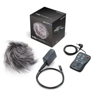 Das Bild zeigt ein Zoom H5 Accessory Pack, bestehend aus einem grauen Fellwindschutz, einer grauen Fernbedienung mit Kabel, einem grauen Adapter mit USB-Kabel und der schwarzen Verpackung des Pakets.