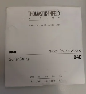 Eine verpackte Thomastik BB40 Single .040 Nickel Round Wound Gitarrensaite A liegt auf einer möglicherweise weißen Oberfläche.