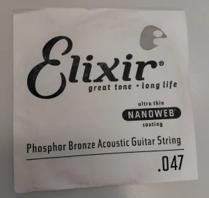 Eine einzelne, verpackte Elixir .047 Phosphor Bronze Akustikgitarrensaite mit ultra dünner Nanoweb-Beschichtung liegt auf einer hellen Oberfläche.