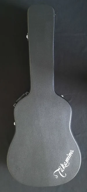 Das Bild zeigt einen geschlossenen, schwarzen Takamine Dreadnoughts Gitarrenkoffer, auf dessen unterem Ende der Takamine-Schriftzug zu sehen ist.