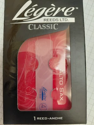 Eine Verpackung für ein Legere Classic Altsaxophon-Blatt der Stärke 4 in rotem Kunststoff unter einer schwarz-weißen Kartonverpackung mit der Aufschrift "Légère REEDS LTD. CLASSIC" und "ALTO SAX".