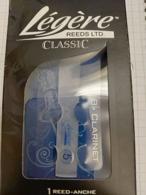 Eine Verpackung des Produkts "Legere Bb Clarinet Böhm Blatt Standard 5" mit der Aufschrift "Légère REEDS LTD. CLASSIC" und der Nummer "5" ist zu sehen, wobei das Blatt selbst durch eine transparente Kunststoffverpackung sichtbar ist.
