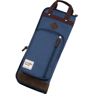 Eine blaue Tama Sticktasche Schwarz TSB24NB mit braunen Akzenten, einem Tragegriff und einer zusätzlichen Außentasche mit Reißverschluss wird frontal auf schwarzem Hintergrund gezeigt.
